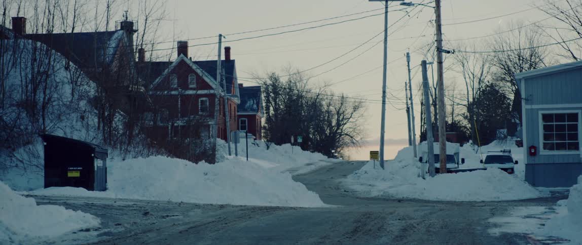 The sun sets behind a hill covered in large snow banks