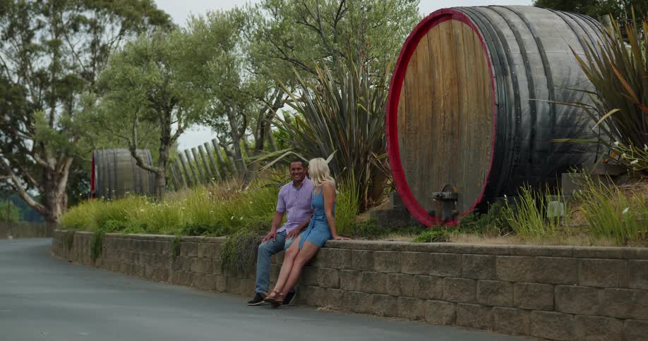 A couple sitting outside near large barrels