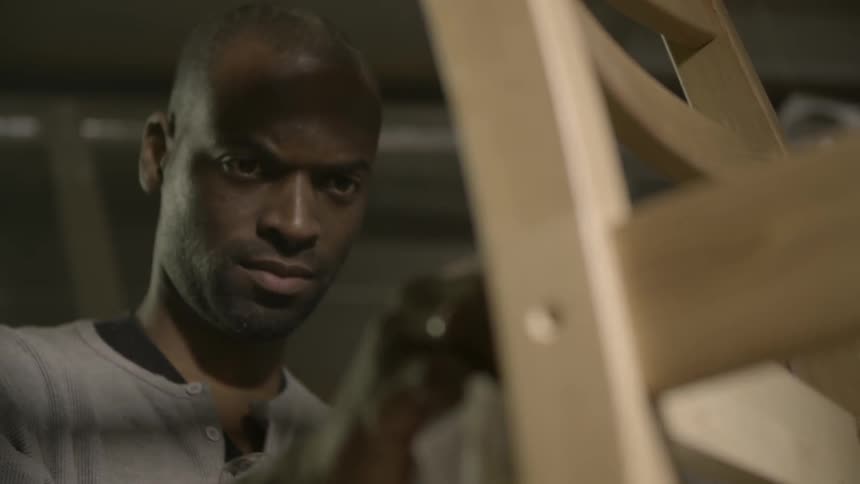 A man is looking at a chair then beings to polish it