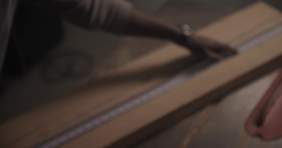 A man measures a piece of wood with a tape measure