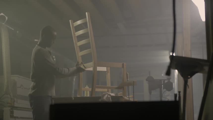 A man puts together a wooden chair