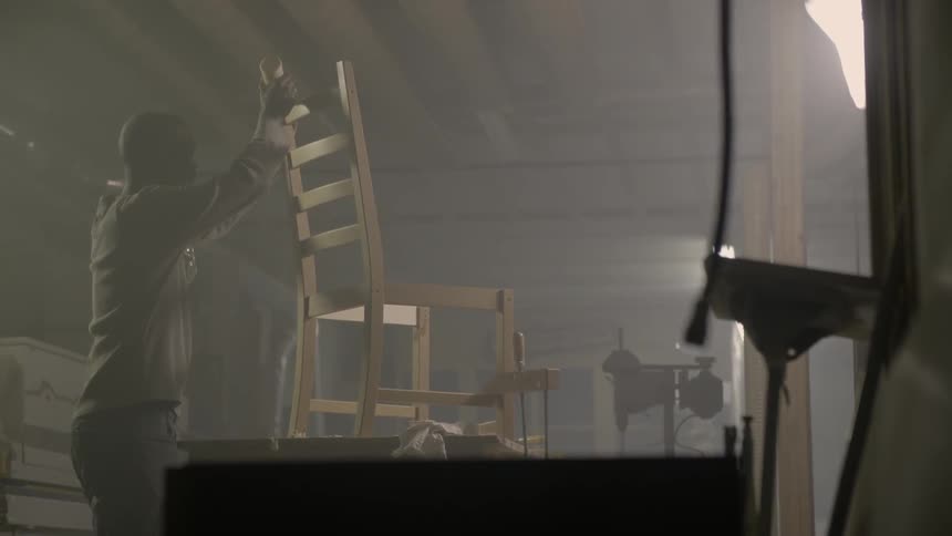 A man is applying glue to a chair on a table