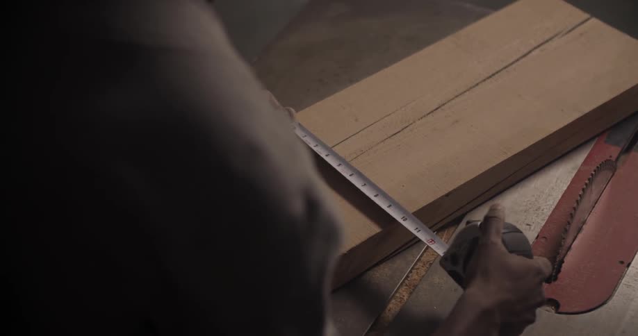 A man is measuring a plank of wood