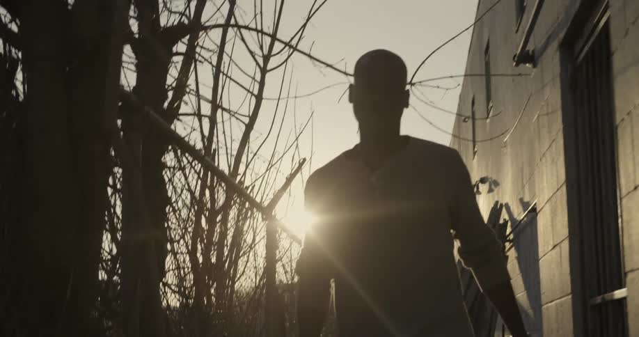 A man walks beside a building at sunset