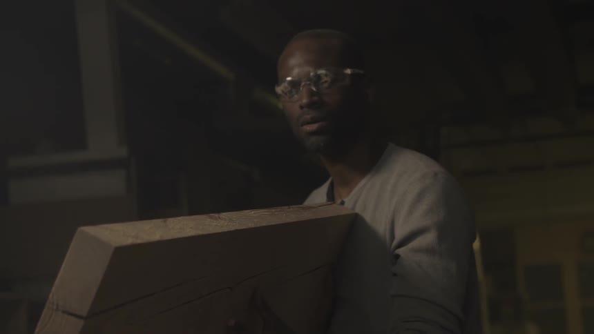 A man blows sawdust off of a large chunk of wood