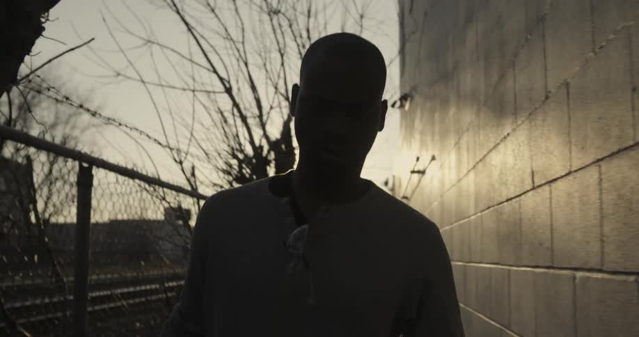 A man is walking near a fence by a building