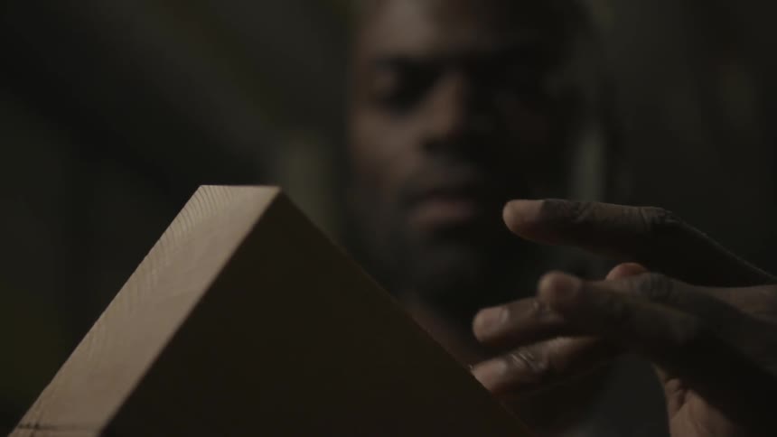 A man traces his hand over a plank of wood