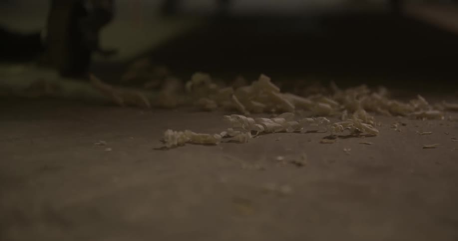 Wood shavings fall onto a concrete floor