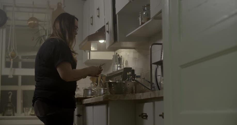 A woman places a bowl on the counter and begins preparing food