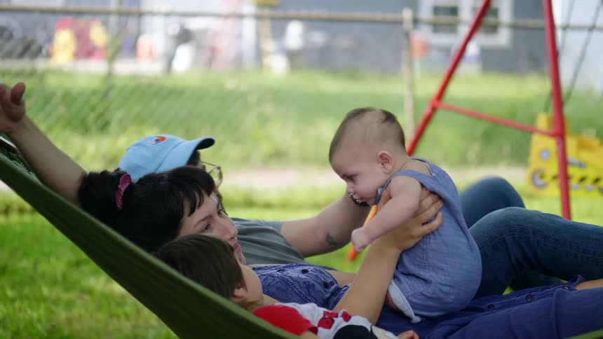 A man lays in the hammock with his family