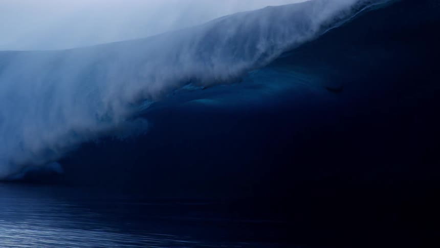 Surfers riding a large ocean wave on a beach