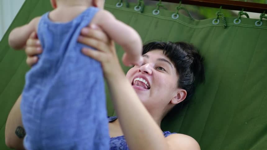 A woman lifts a baby up and down in the hammock