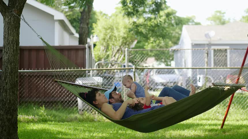 A family is laying in a hammock together