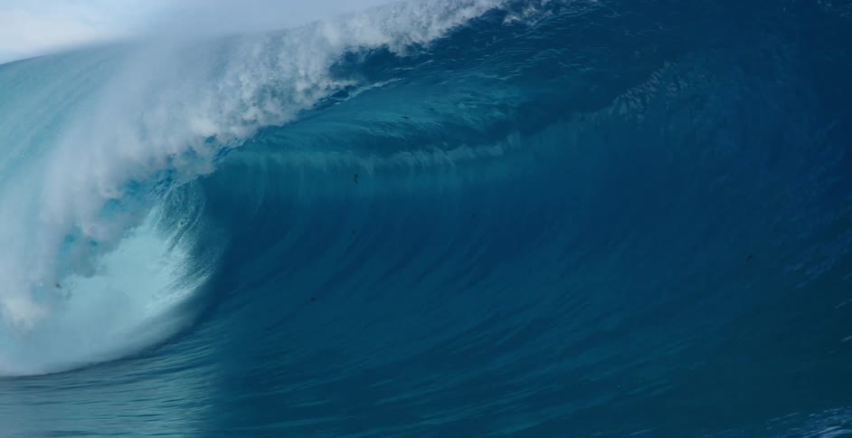 A large ocean waves crests amid a spray of foam