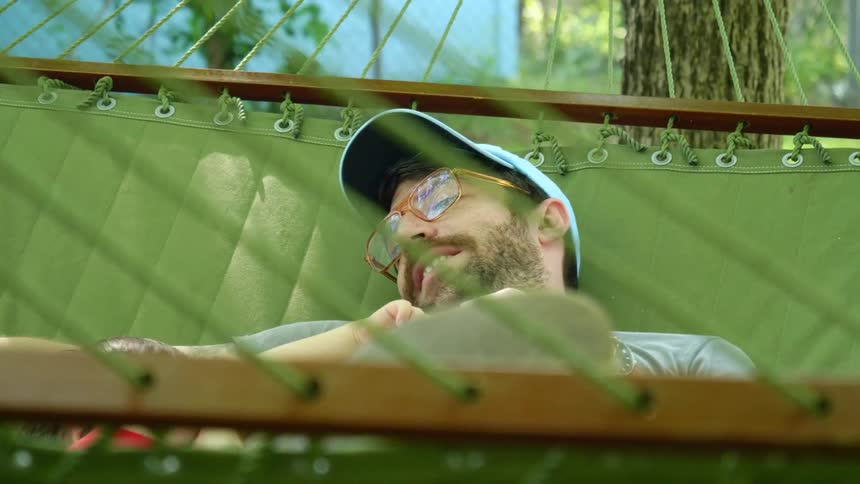 A dad lies in a hammock with his young son and talks to him