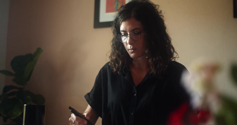 A woman uses a marker to draw in a notebook while sitting at a table during the day