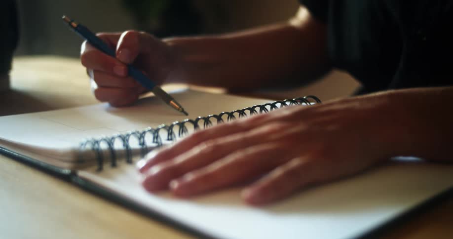 A person is writing in a notebook
