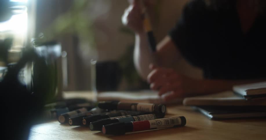 A person sitting at a table with markers writing on a notebook