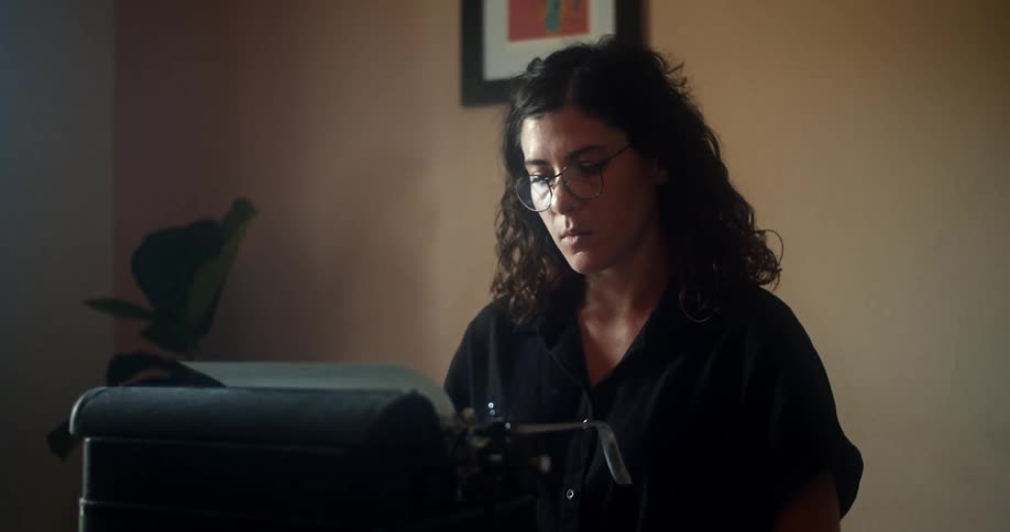 A woman is sitting in a room and typing on a typewriter