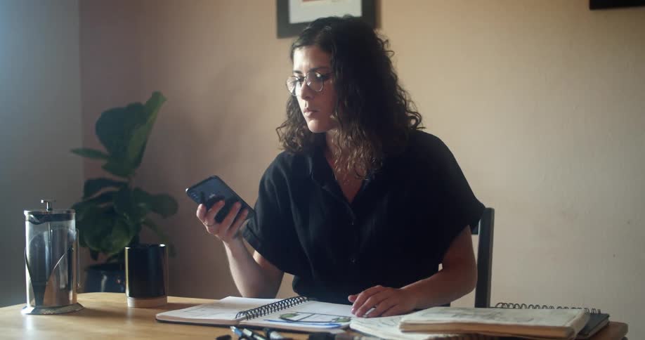 A woman working in an office answers her cell phone and looks towards the window