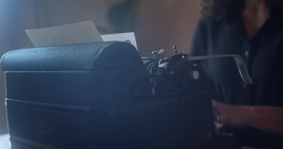 A woman is typing on a typewriter indoors