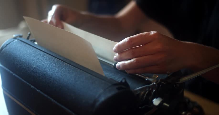 A person sitting at a table typing on a typewriter