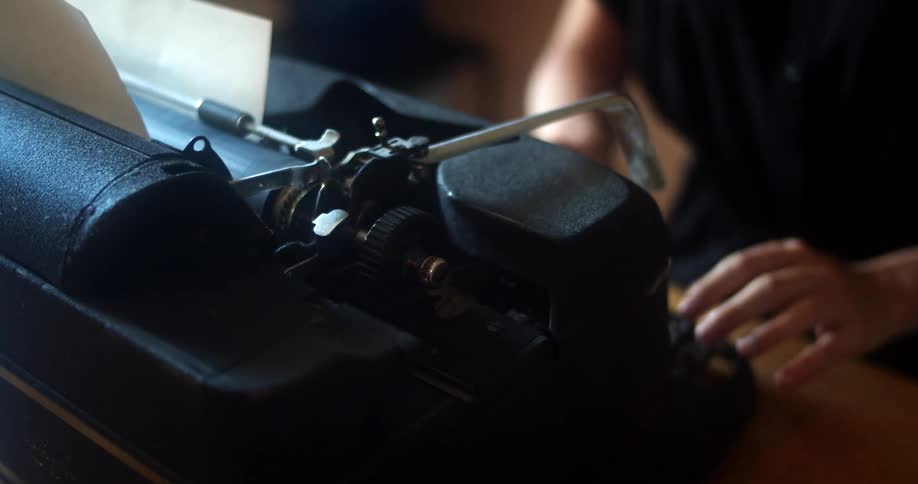 A person sitting at a table typing on a typewriter