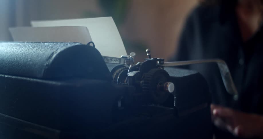 A woman at home types on a vintage typewriter