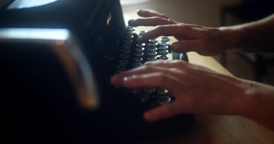 A person is typing on a typewriter indoors