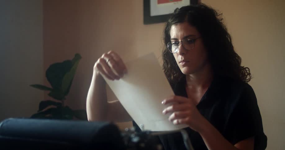 A woman removes a paper from the typewriter