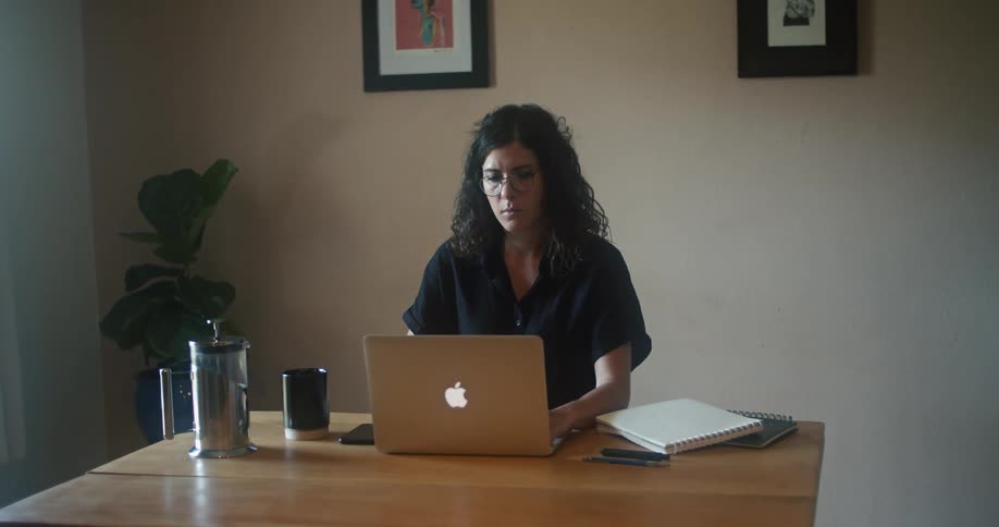 A woman is typing on a laptop while sitting at a desk