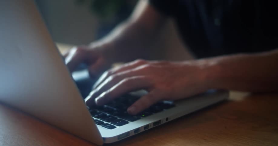 A person is sitting at a desk and typing on a laptop