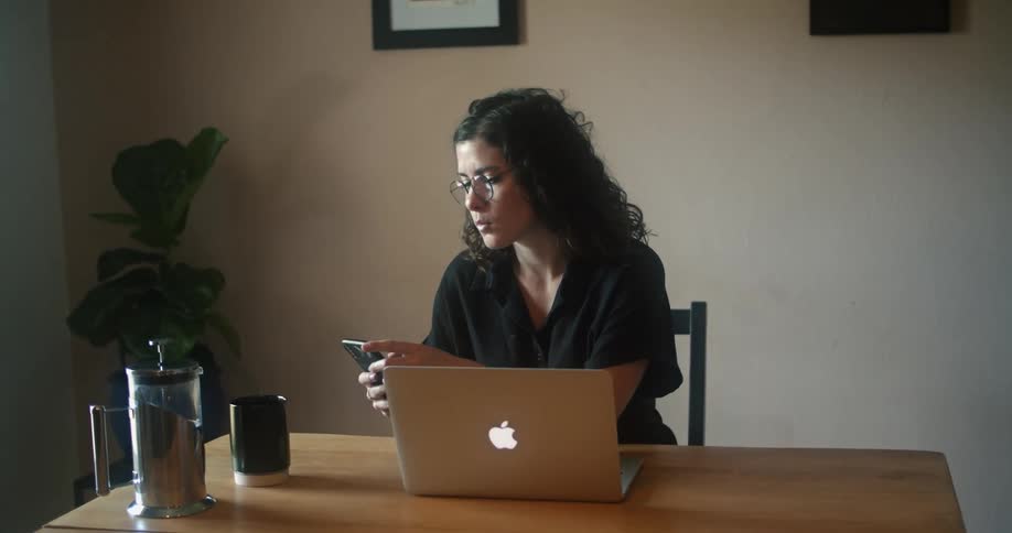 A woman is sitting at a desk and using a laptop