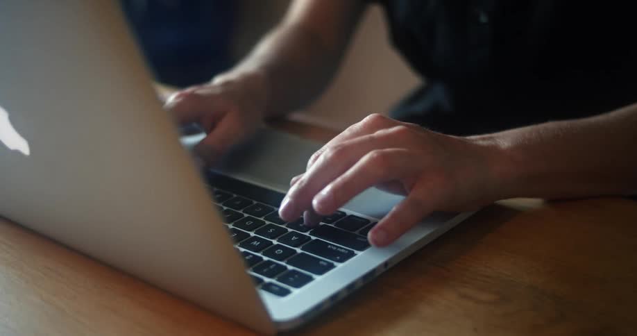 A person sitting at a table typing on a laptop