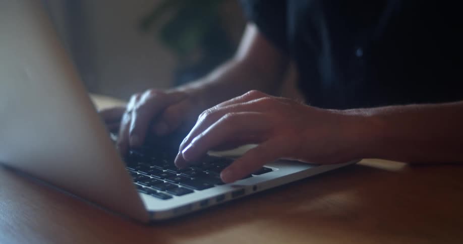 A person is typing on a laptop indoors