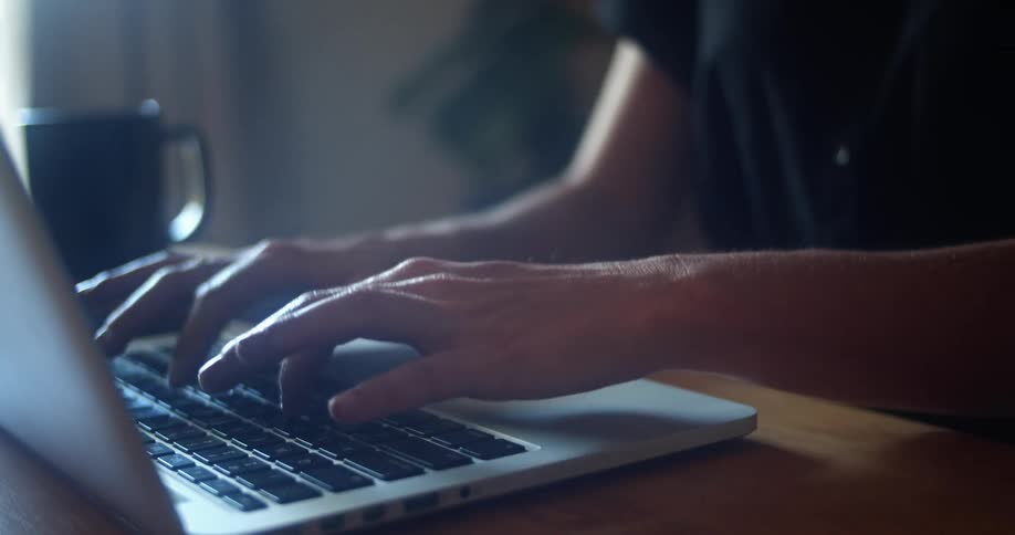 A person is typing on a laptop indoors