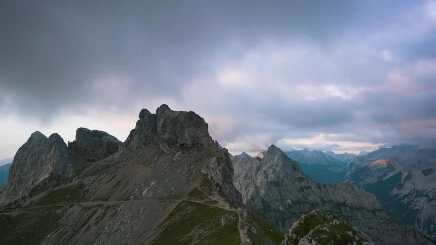 Clouds pass over a gray mountain ridge during the day