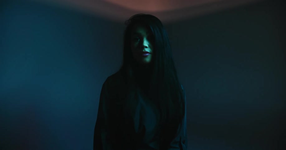 A young woman standing in a room with a light flashing