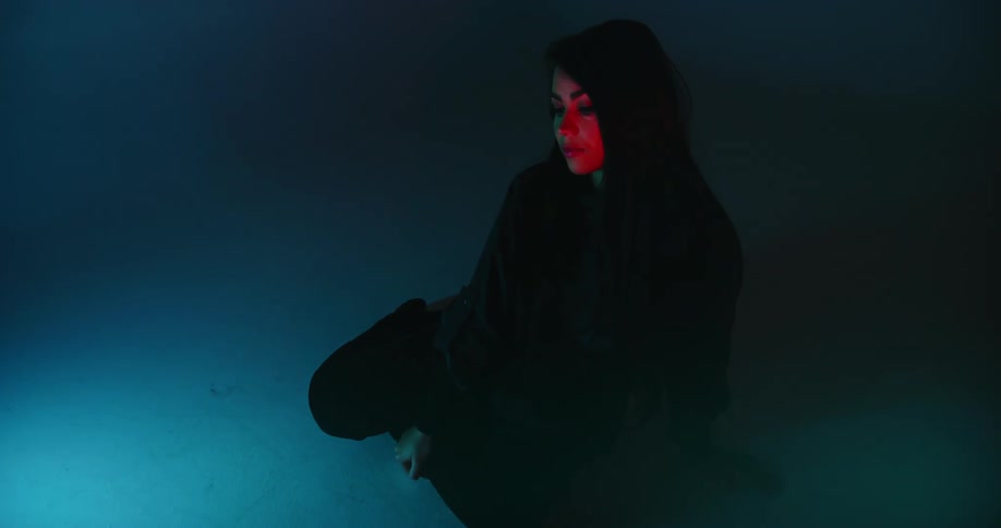 A woman sitting on the floor with lights flashing on her face