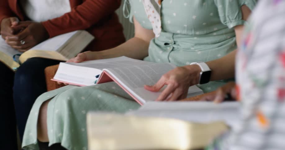 A group of women sit together while reading from thick books