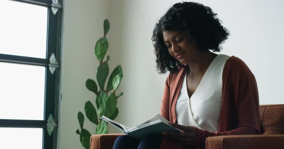 A woman is sitting on the chair reading a book