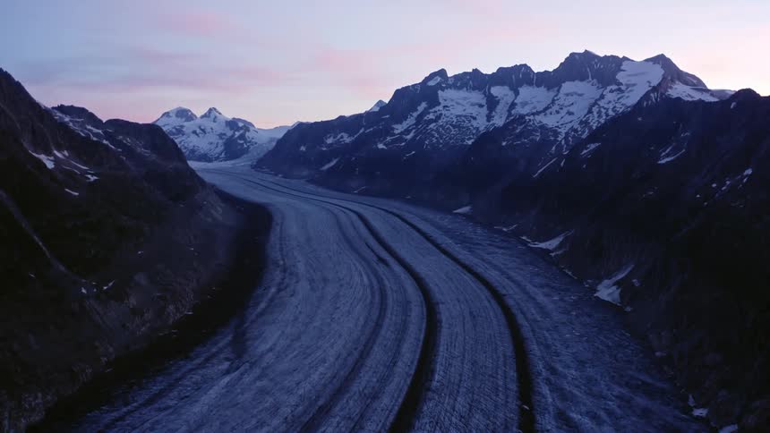 Tire tracks run through snow covered ground in the valley of a canyon