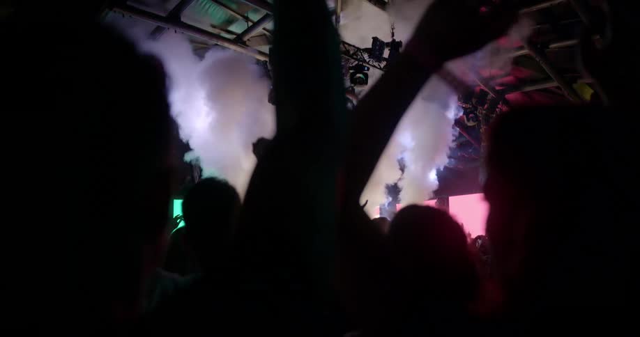 The crowd of a night club cheers as steam shoots into the air