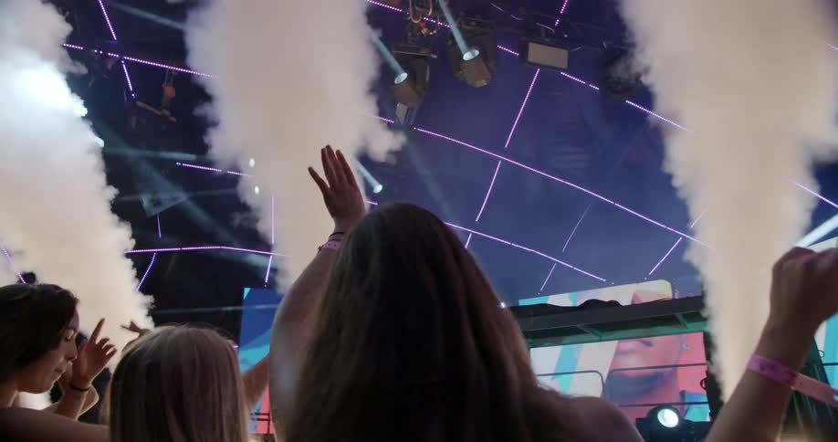 Smoke rises in to the air as women dance at a concert