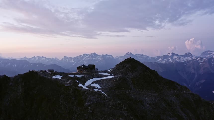 Building sits on snowy flat plateau on top of mountain in mountain range