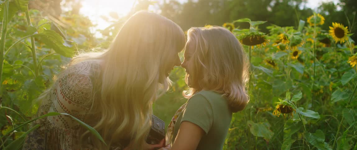 Mother and daughter have fun laughing in a field of sunflowers at sunset