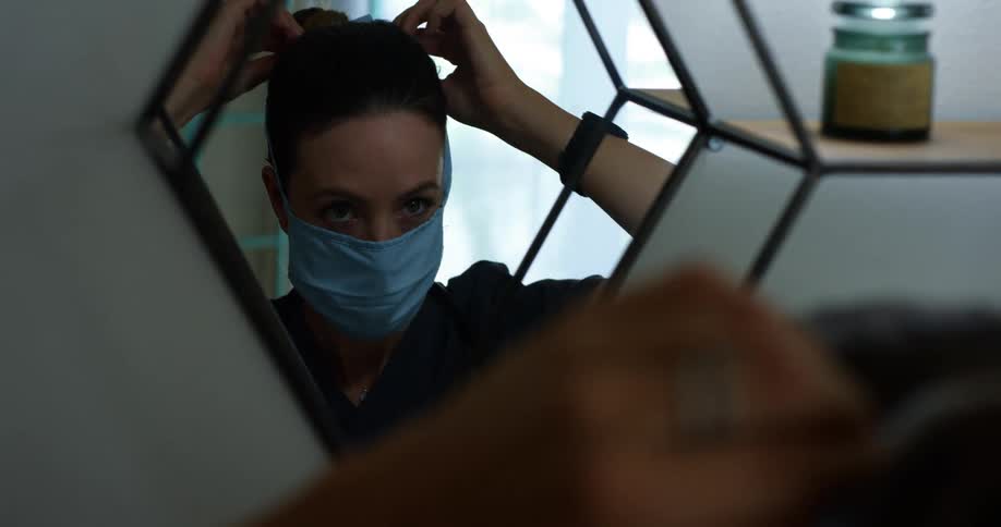 A nurse is putting on her face mask
