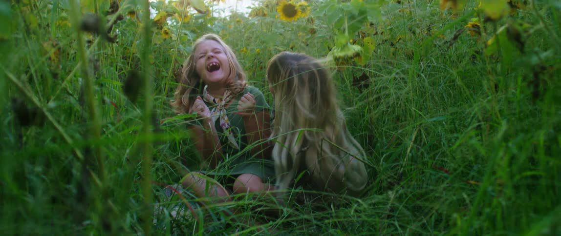 A woman and child play in the sunflower patch