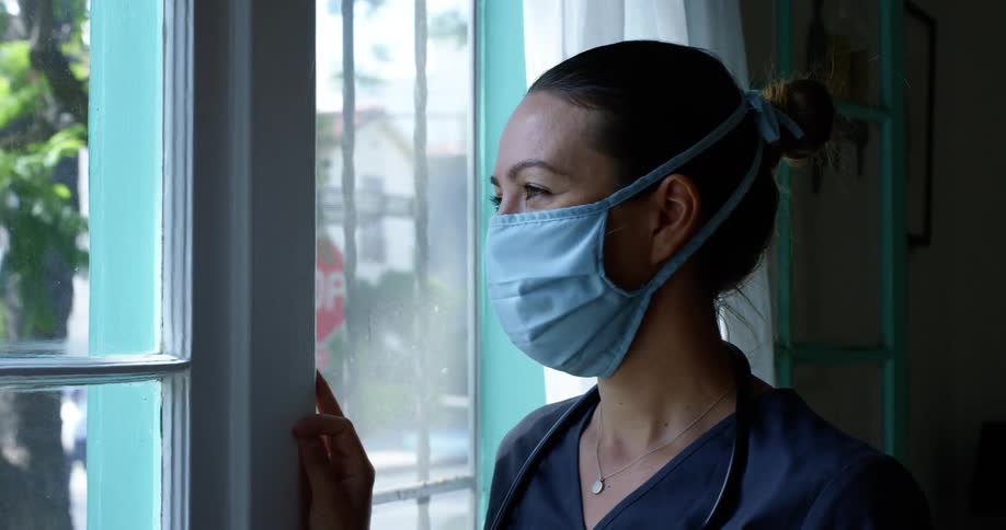 A nurse stands by a large door and window looking to the outside