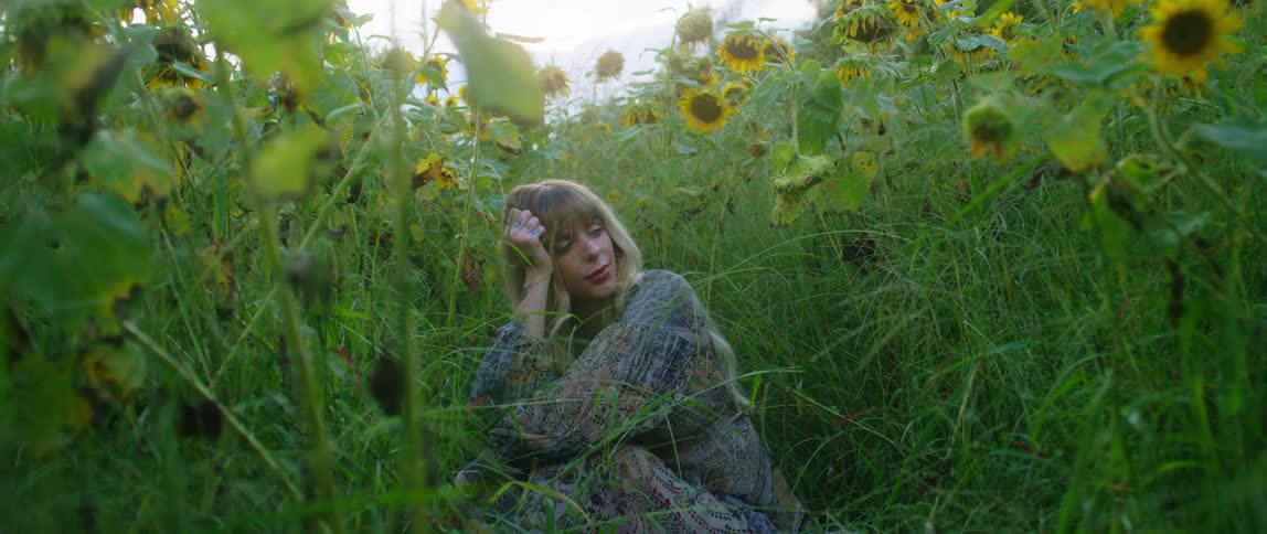 A woman is looking at flowers in a meadow
